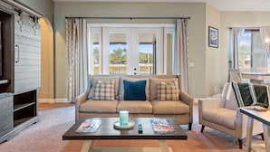 Una sala de estar con un sofá color beige, una mesa de centro y un mueble para televisión.