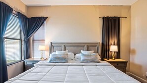 Una habitación de hotel con una cama grande, dos mesitas de noche con lámparas y una ventana con cortinas.