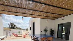 Une terrasse extérieure avec une table et des chaises, un luminaire suspendu et une vue sur le paysage.