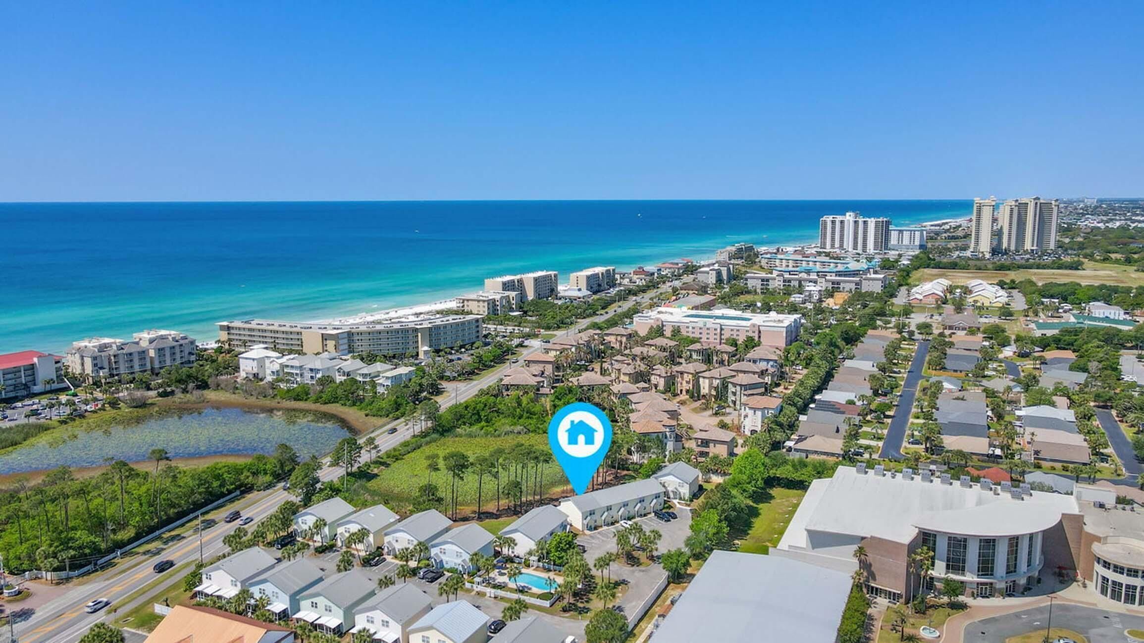 A coastal resort area with multiple buildings, including hotels and residential structures, near a beach with clear blue waters.