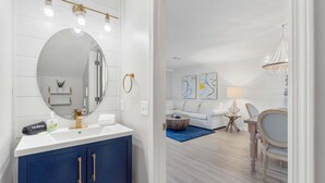 A modern bathroom with a large mirror, white vanity, and gold fixtures. - Summer Lake 15- Shore to Please (Miramar Beach)