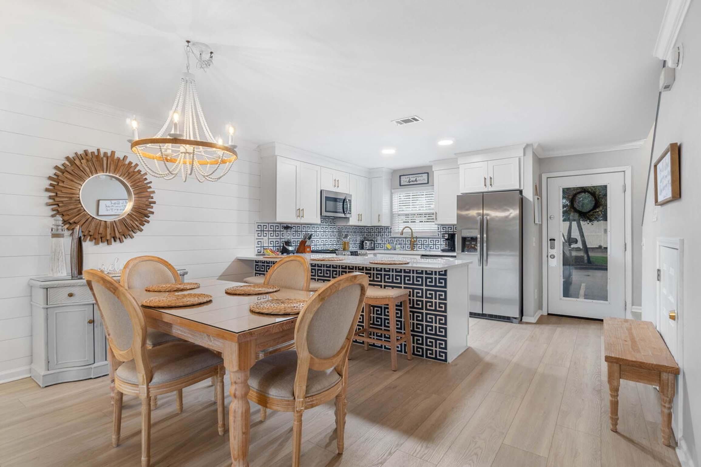 A modern kitchen with white cabinetry, a central island, and a chandelier.