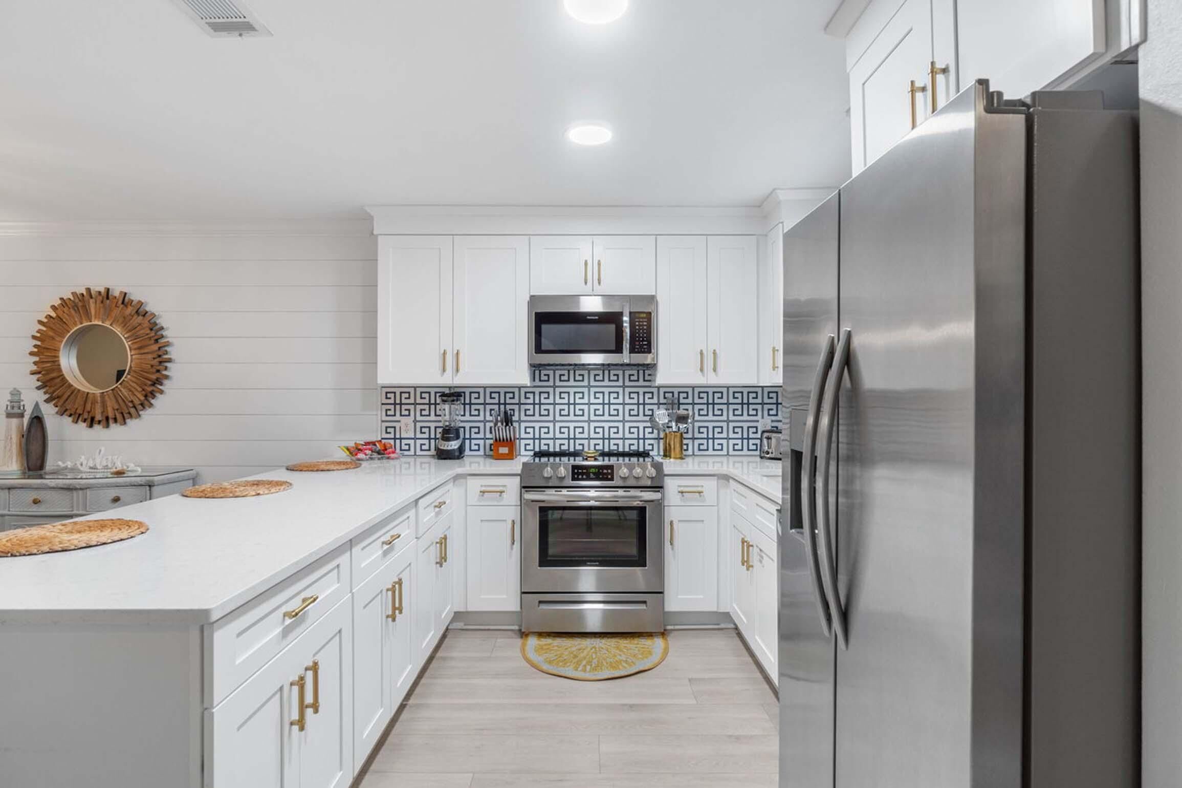 A modern kitchen with white cabinetry, stainless steel appliances, and decorative backsplash tiles.
