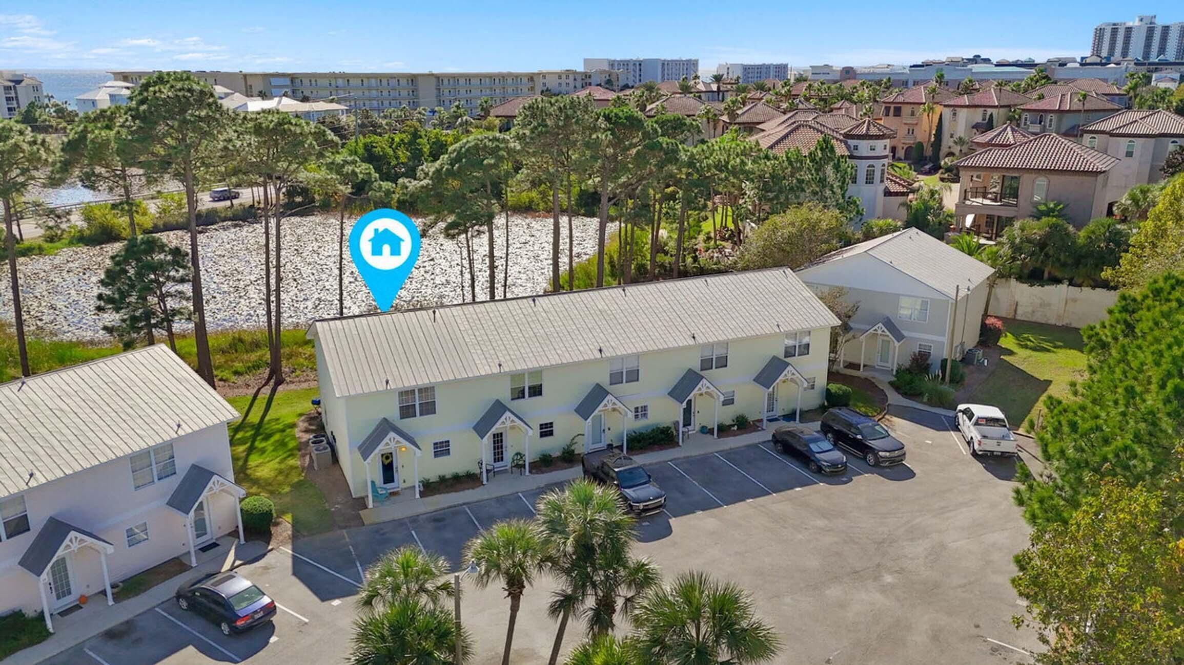 A multi-story hotel with a parking lot, surrounded by palm trees and other buildings.