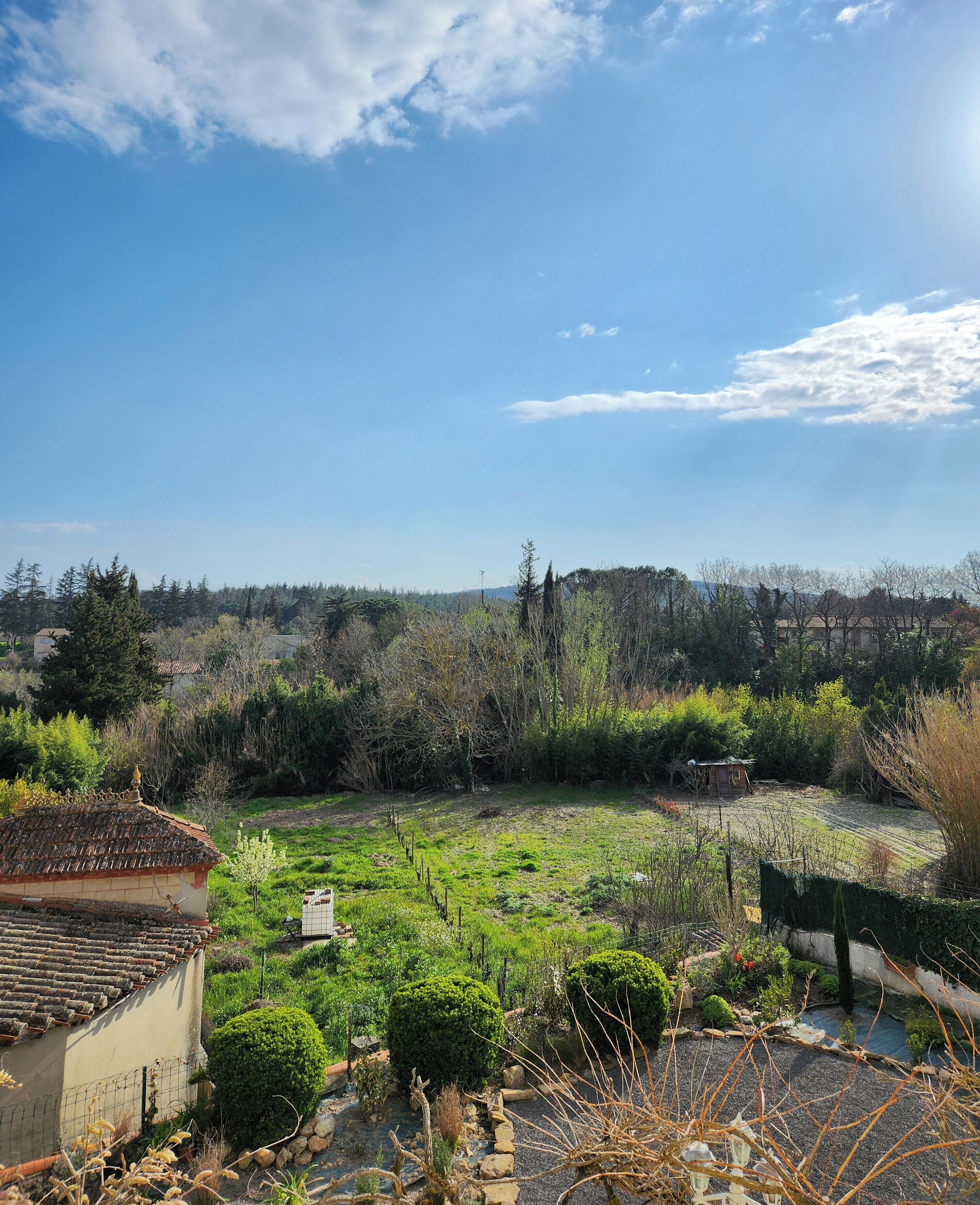 Ländliche Landschaft mit einem Haus, einem Garten und blauem Himmel.