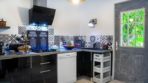A modern kitchen with black and white patterned tiles, a dishwasher, a stove, and a window with a view of greenery.