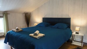 A bedroom with a large bed, two bedside tables with lamps, and a window with curtains.