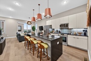 A modern kitchen with a central island, stainless steel appliances, and pendant lighting.