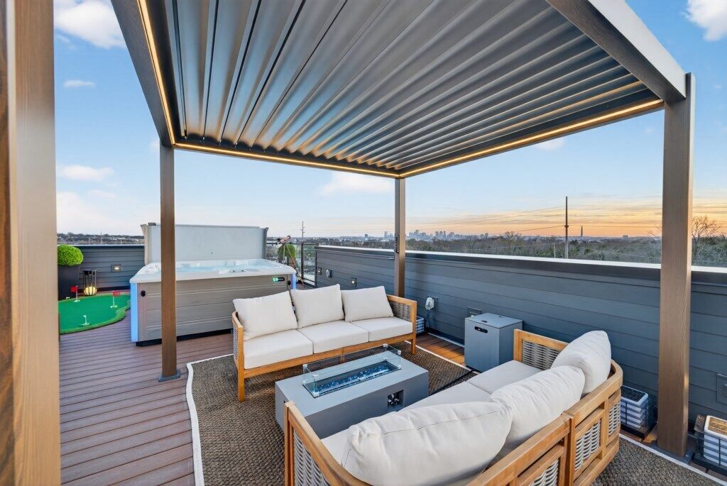 A rooftop terrace with a wooden deck, a hot tub, a sofa, and a small table.