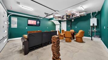 A modern, well-lit room with teal walls, a black sofa, and orange chairs. There is a large window, a white door, and a visible water heater.