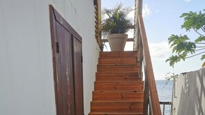 A wooden staircase leading to a balcony with a potted plant on the landing. - New! Tikanot'la haut Exceptional view of Grande Anse beach (Deshaies)