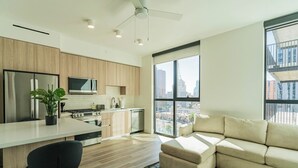 A modern kitchen with wooden cabinets, a central island, and a dining area. - Saiya  920 (Phoenix)