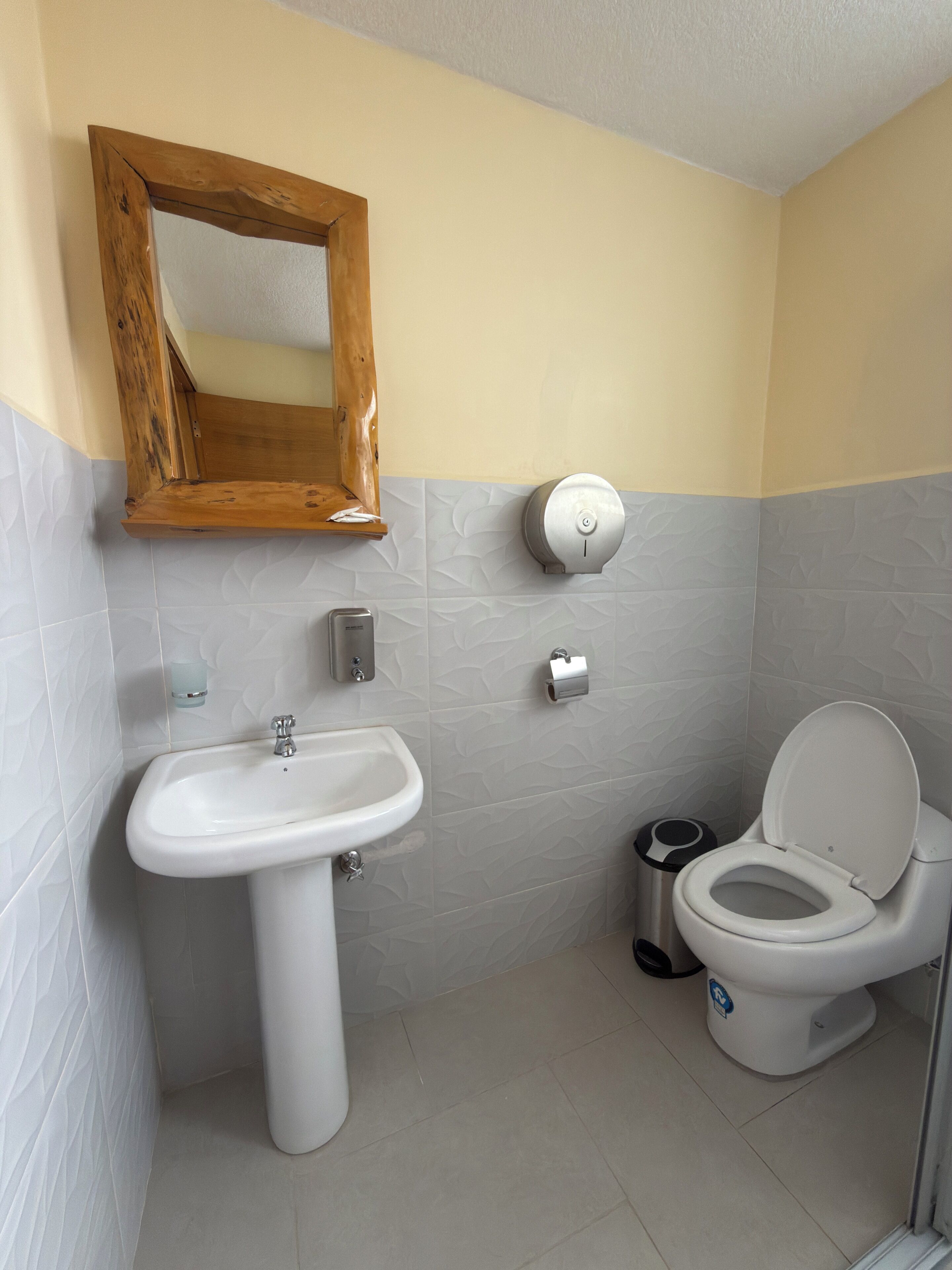 A bathroom with a sink, toilet, and a hand dryer.