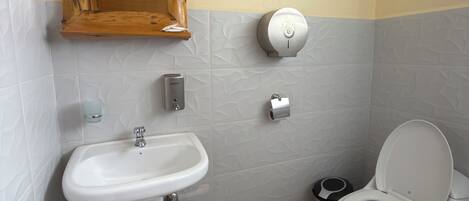 Ein Badezimmer mit Waschbecken, Toilette und einem Händetrockner.