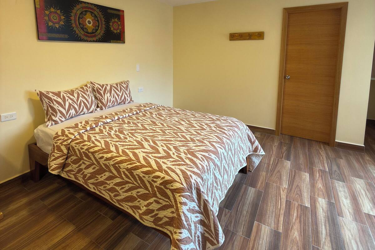 Een slaapkamer met een bed, een houten deur en een wandlamp.