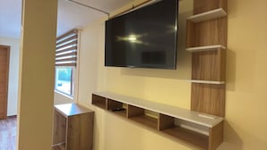 Een moderne woonkamer met een flatscreen televisie aan de wand, houten kasten en een houten vloer.