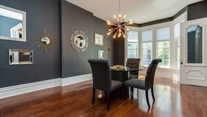 Un espace repas avec un mur de couleur sombre, un lustre et une grande fenêtre.