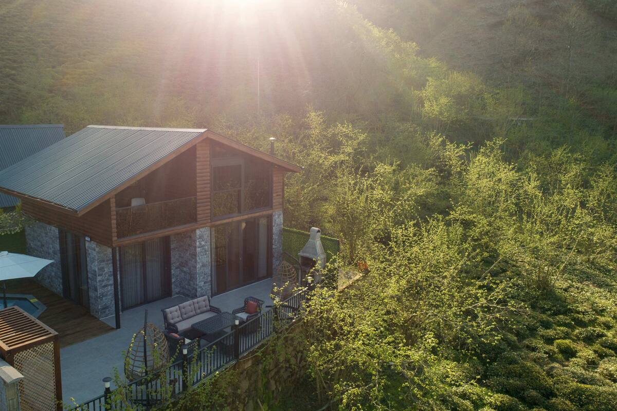 A modern house with a deck, surrounded by lush greenery.