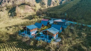 Una casa moderna con varias habitaciones, piscina y vistas a las colinas circundantes.