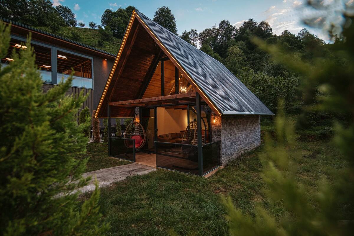 A modern house with a sloped roof, a glass entrance, and a cozy interior with seating.