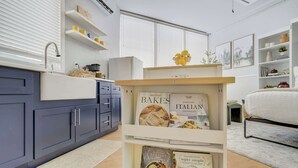 Une cuisine moderne avec des meubles de couleur bleu foncé, un plan de travail blanc et une bibliothèque intégrée où sont exposés des livres de cuisine.