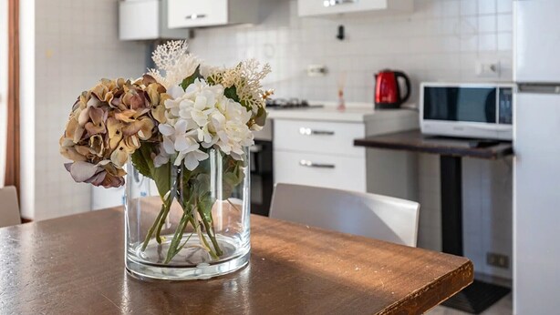 A kitchen with white cabinets, a microwave, and a red kettle on the counter. - Room 'Camera Tripla' with Shared Terrace, Wi-Fi and Air Conditioning (San Zeno)