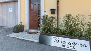 Un immeuble avec une porte marron, une boîte aux lettres et une enseigne indiquant « Boccadoro Rooms ».