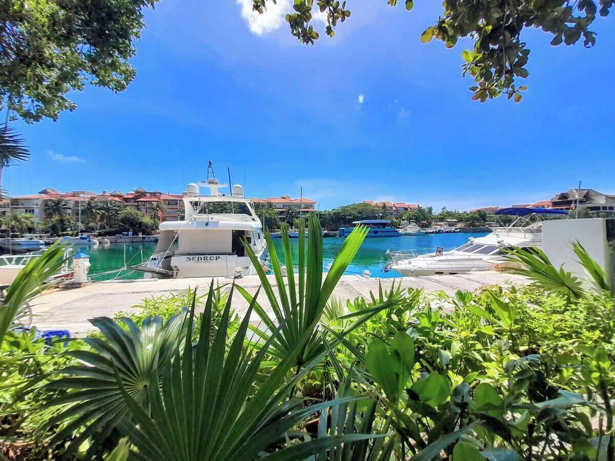 Un port de plaisance avec des bateaux amarrés, un yacht nommé « SEDROP » et un ciel bleu azur.