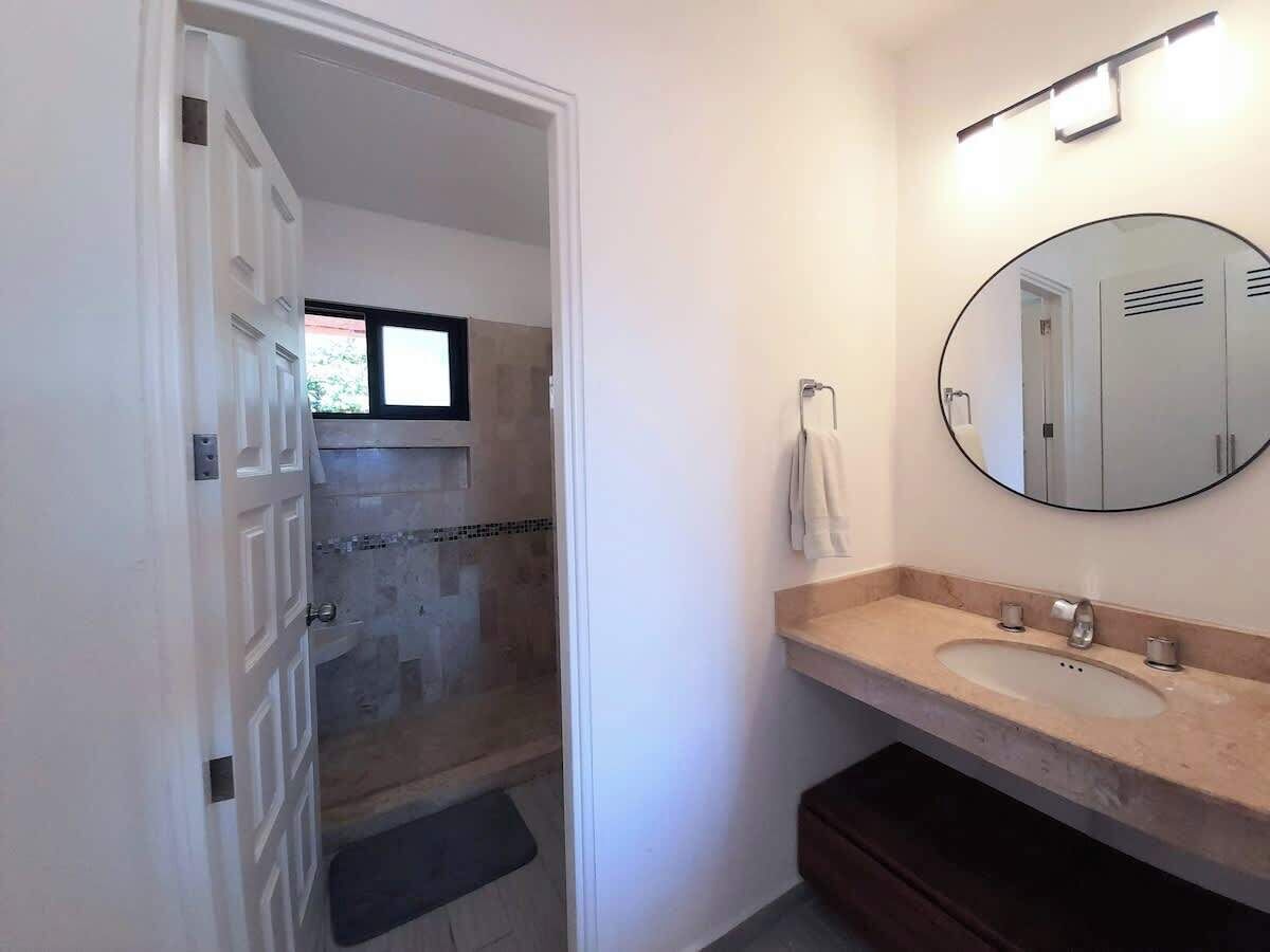 A bathroom with a shower, a sink, a mirror, and a towel hanging on the wall.