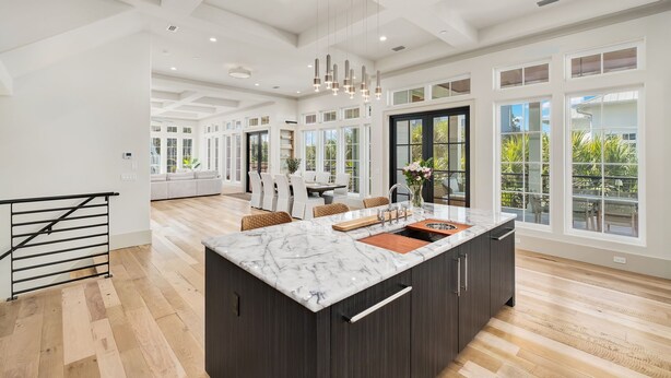 A modern kitchen with a marble island, large windows, and a dining area with a view. - Seaside Thyme|Private Pool|Steps to Seaside|Golf Cart (Santa Rosa Beach)