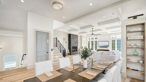 A spacious dining area with a long table, white chairs, and a modern ceiling design. - Seaside Thyme|Private Pool|Steps to Seaside|Golf Cart (Santa Rosa Beach)