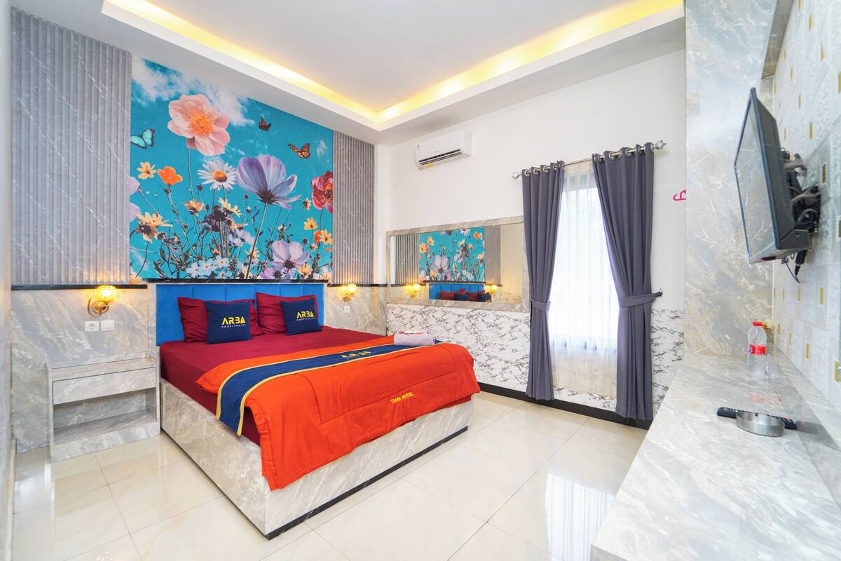 A modern bedroom with a large bed, a mural on the wall, and a TV mounted on the wall.