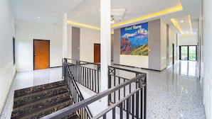 A hotel lobby with a marble staircase, a large mural of a mountain landscape, and a modern design with white walls and ceiling lights. - Hotel Tiara by ARBA (Weleri)