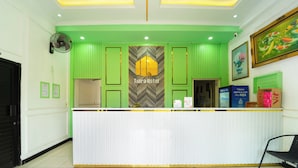 A hotel reception area with a green and white color scheme, a reception desk, a fan, and a framed painting on the wall. - Hotel Tiara by ARBA (Weleri)