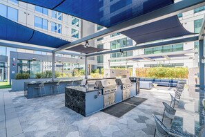 An outdoor patio with a barbecue grill, seating area, and a view of the building's exterior. - Kenect 916 (Phoenix)