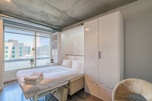 A modern hotel room with a large bed, a wardrobe, and a view of the city. - Kenect 916 (Phoenix)
