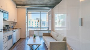 A modern apartment with a kitchen, a sofa, and a large window with a city view. - Kenect 916 (Phoenix)