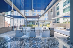 An outdoor kitchen area with a hot tub, grill, and seating. - Kenect 916 (Phoenix)
