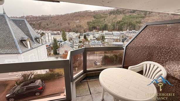 Uma varanda com vista para uma cidade, uma cadeira e um carro estacionado lá fora.