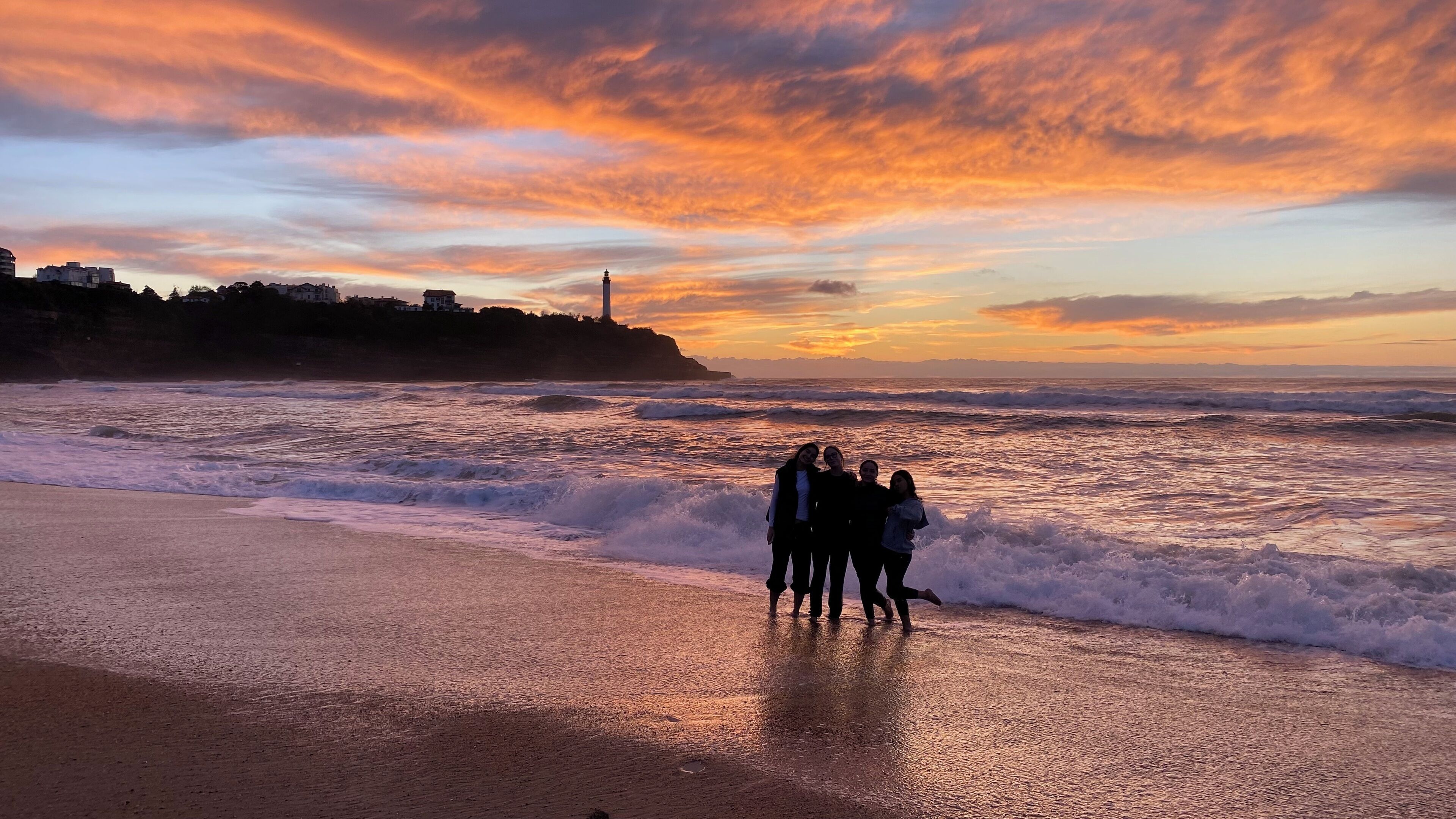 Escena de playa con olas y un atardecer.