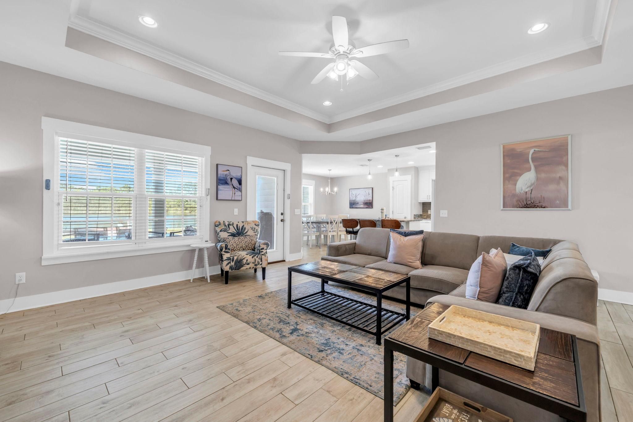 A spacious living room with a large sofa, a coffee table, and a dining area in the background.
