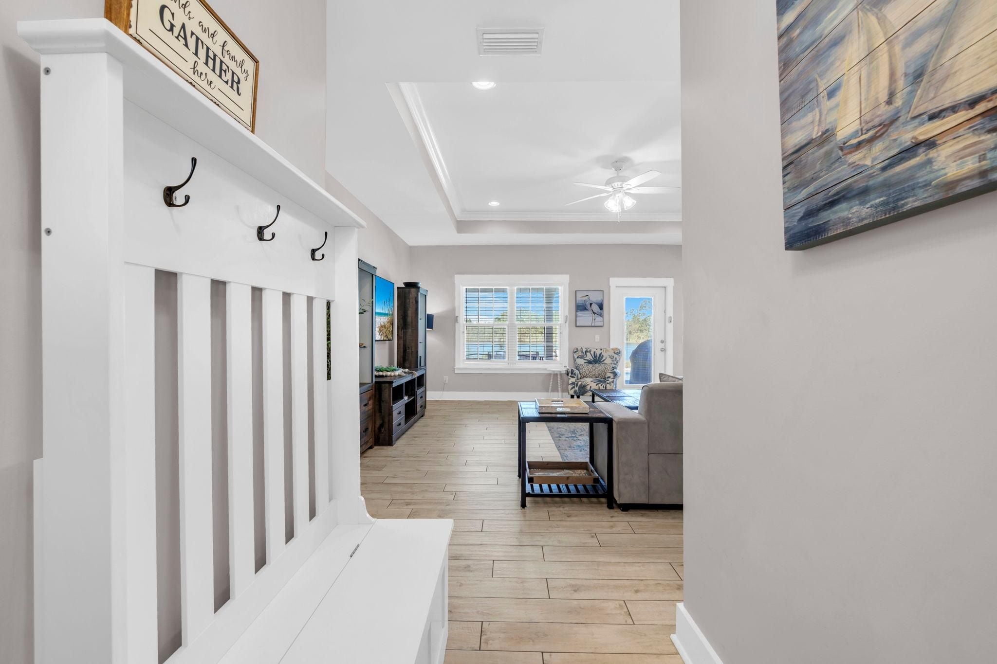 A hallway leading to a dining area with a view of the outdoors through a window.