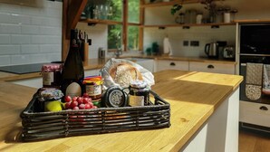 Un comptoir de cuisine sur lequel se trouve un panier en osier contenant divers aliments, une bouteille de vin et une miche de pain.