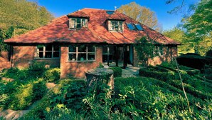 Une maison en briques avec un toit rouge, de grandes fenêtres et un jardin.