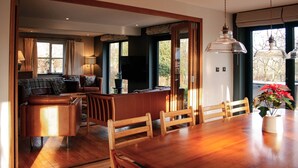 Un vaste espace de vie comprenant une table à manger en bois, des chaises, un canapé et un téléviseur.
