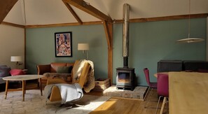 A cozy living room with a fireplace, a sofa, a chair, and a table. - Kent Family Retreat · Stable + Shepherd's Hut (Cranbrook)