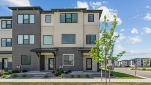 A modern multi-story apartment building with a flat roof, large windows, and a well-maintained lawn.