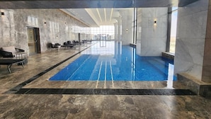 Ein großzügiger, überdachter Pool mit freier Aussicht auf die Stadt durch große Fenster.