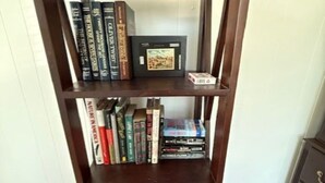 A tall wooden bookshelf with multiple shelves, some filled with books and one with a framed picture.