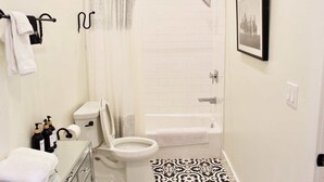 A bathroom with a toilet, bidet, shower, and bathtub. There are towels and toiletries on the counter. - Lodges Combined Suite on the Mason Tx Square (Mason)